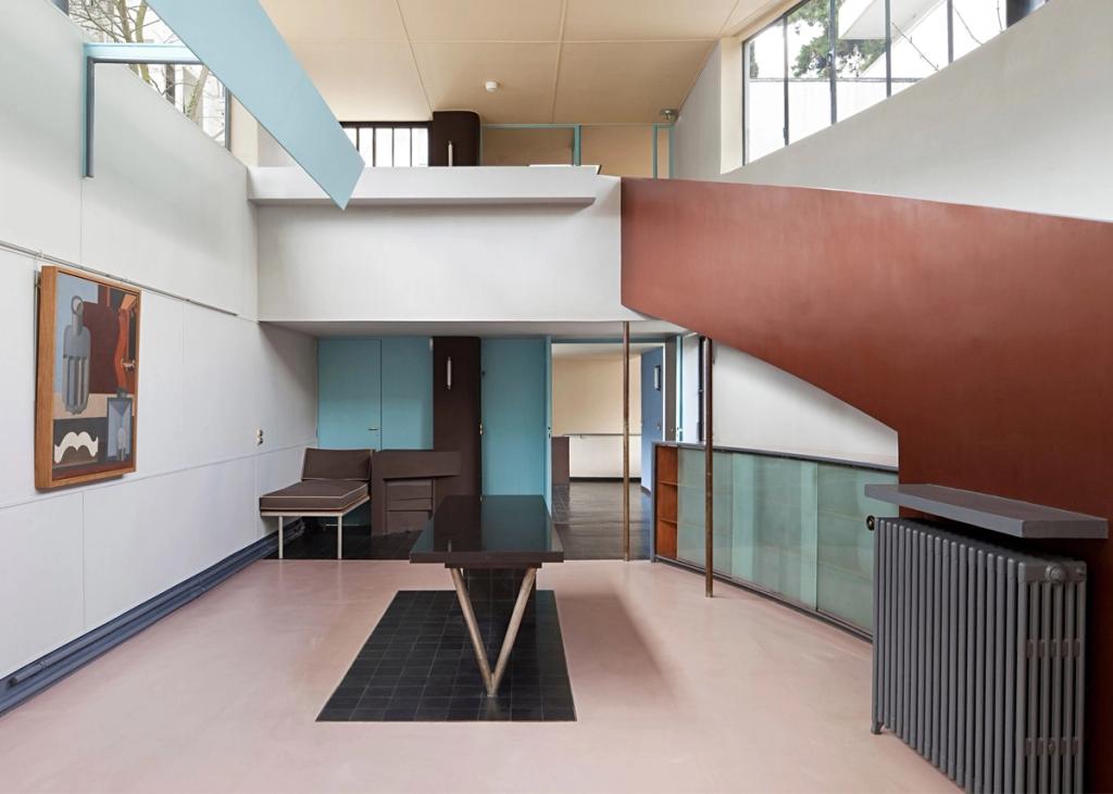 The double-height hall of Villa La Roche with a ramp, a painting, and a pink floor