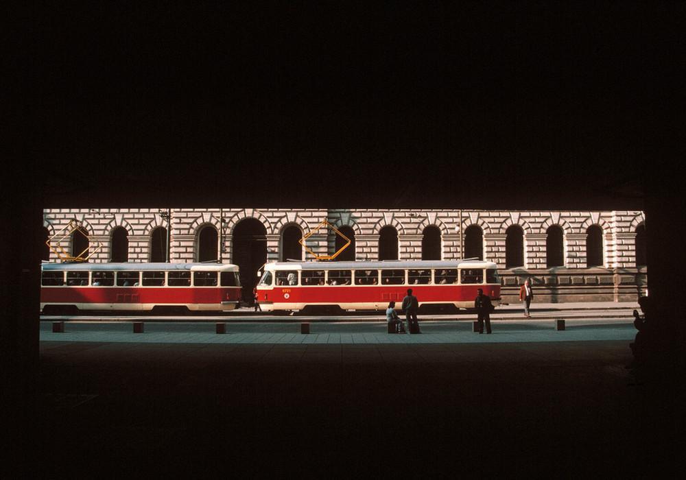 Red-and-white trams beside an arcade lit by a strip of light in the darkness