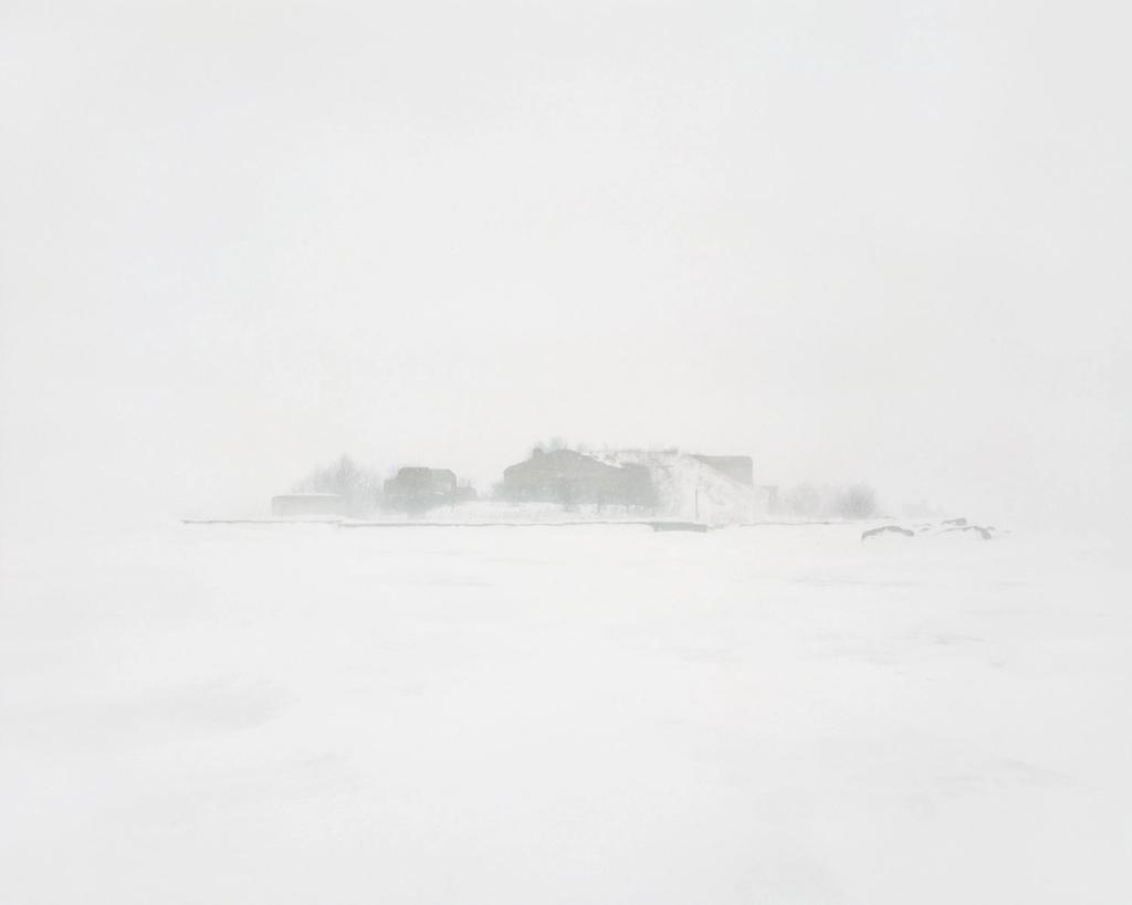 Silhouettes of buildings and machinery, barely discernible in a thick blizzard