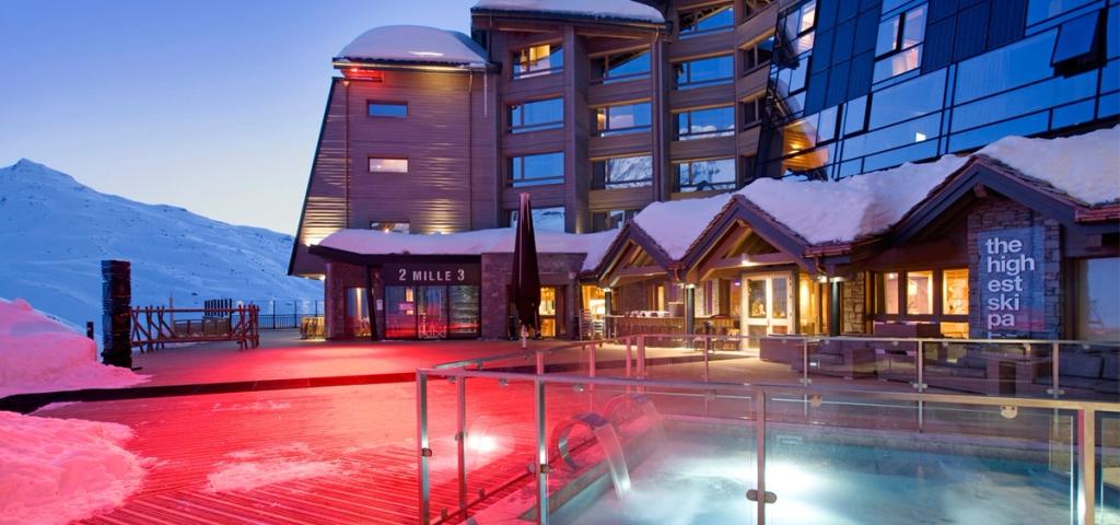 The illuminated façade of Altapura in Val Thorens and an outdoor pool on a winter evening