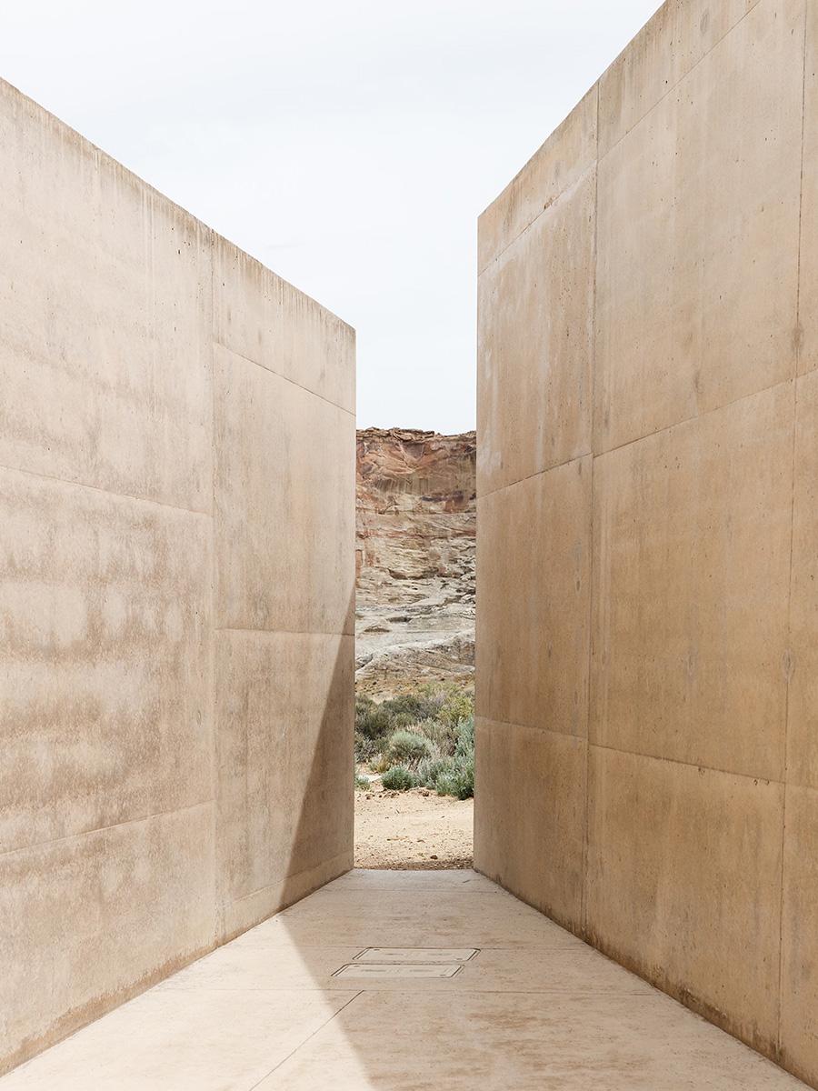 A narrow passage between the high concrete walls of Amangiri, with views of the desert rock formations