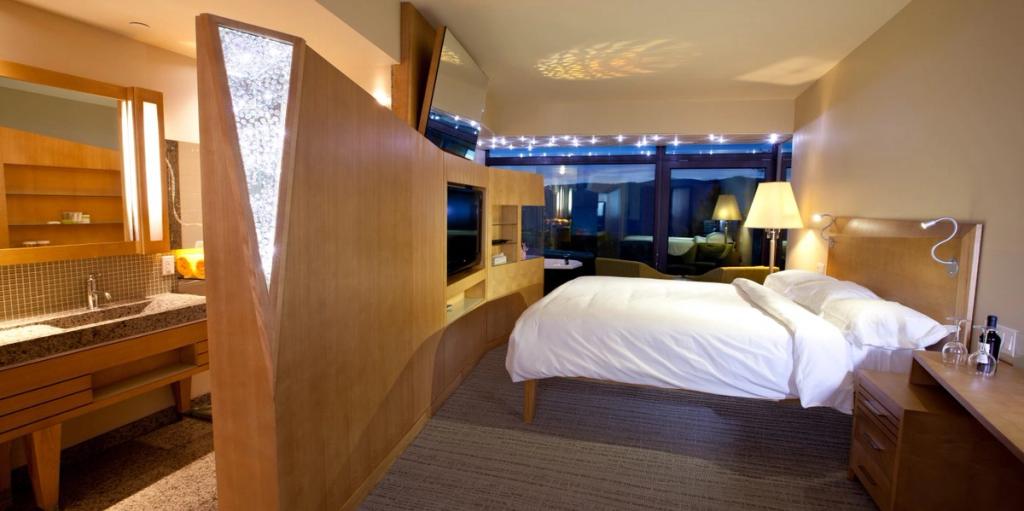 A Sparkling Hill guest room with a bed, wooden partition and ambient ceiling lighting