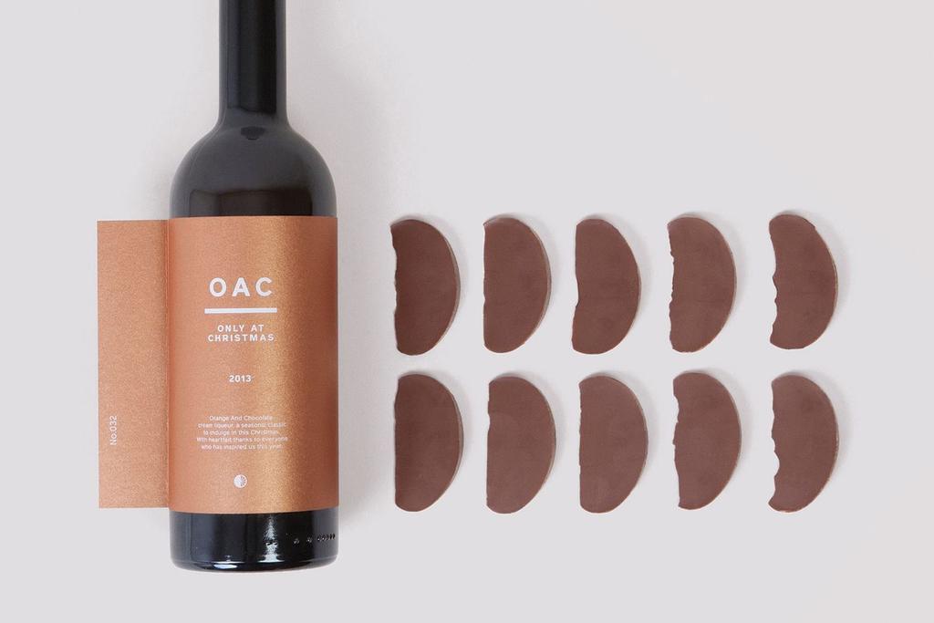 Лежащая бутылка ликёра OAC с медной этикеткой и шоколадные дольки рядом
