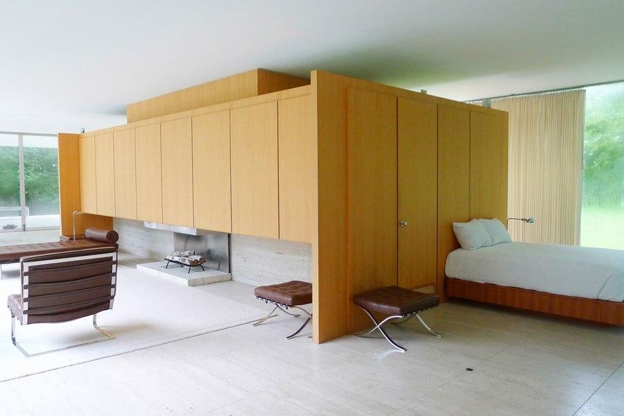 Sleeping area of the Farnsworth House with a wooden wardrobe core and a bed beside the glass wall