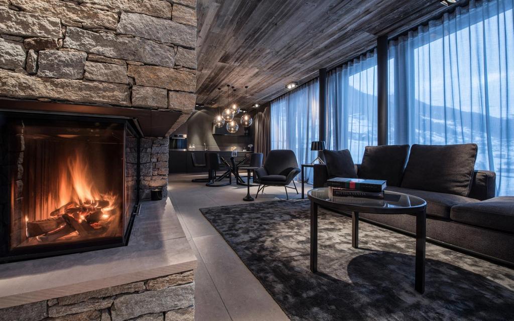 A suite living room with a stone fireplace, sofa and window onto the snowy mountains