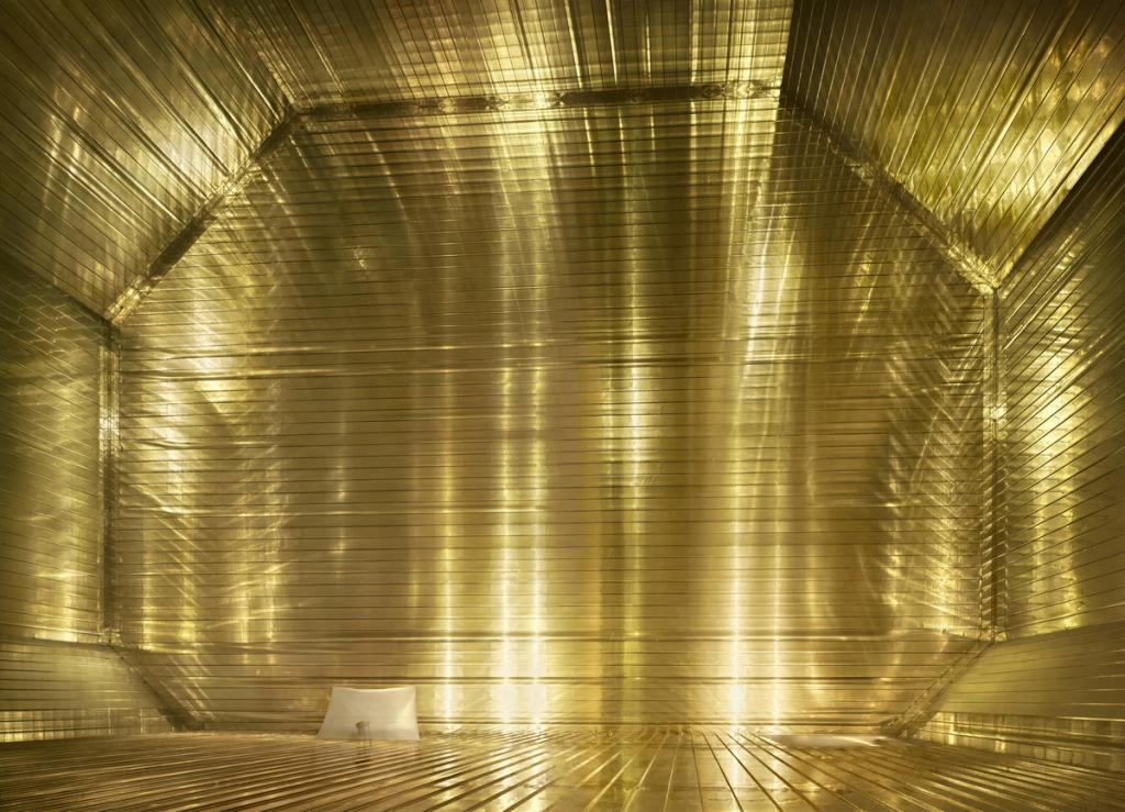 A luminous golden interior with mirrored walls and a solitary white object on the floor