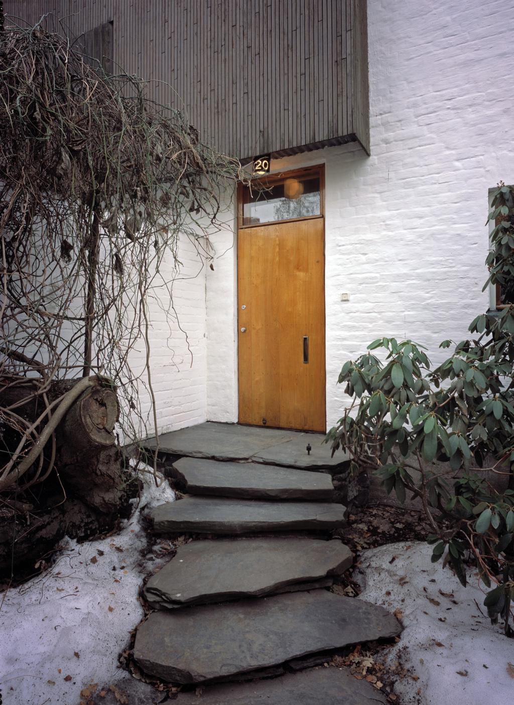 The wooden entrance door of the Aalto house, numbered 20, with stone steps in winter