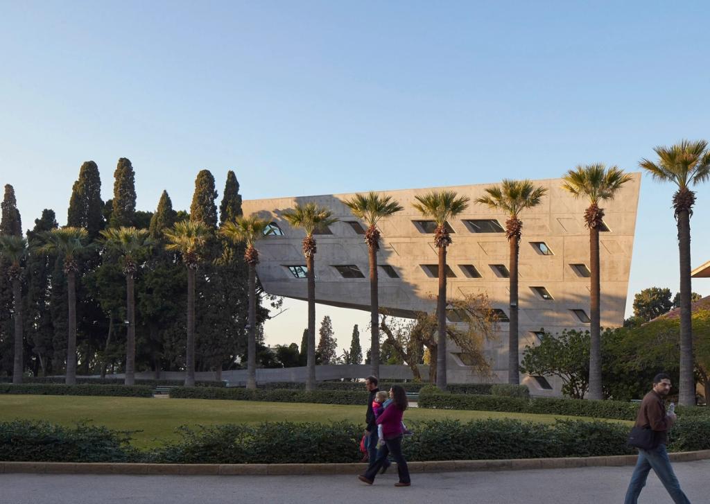 Консольный бетонный корпус Института Иссама Фареса Захи Хадид среди пальм и кипарисов