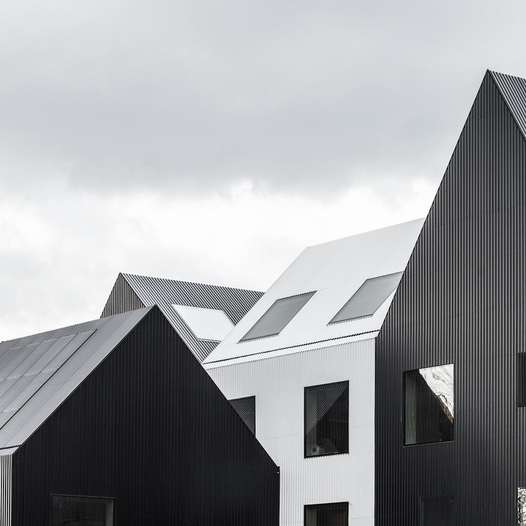 The black and white gabled roofs of the COBE Architects kindergarten, with dormer windows, set against an overcast sky