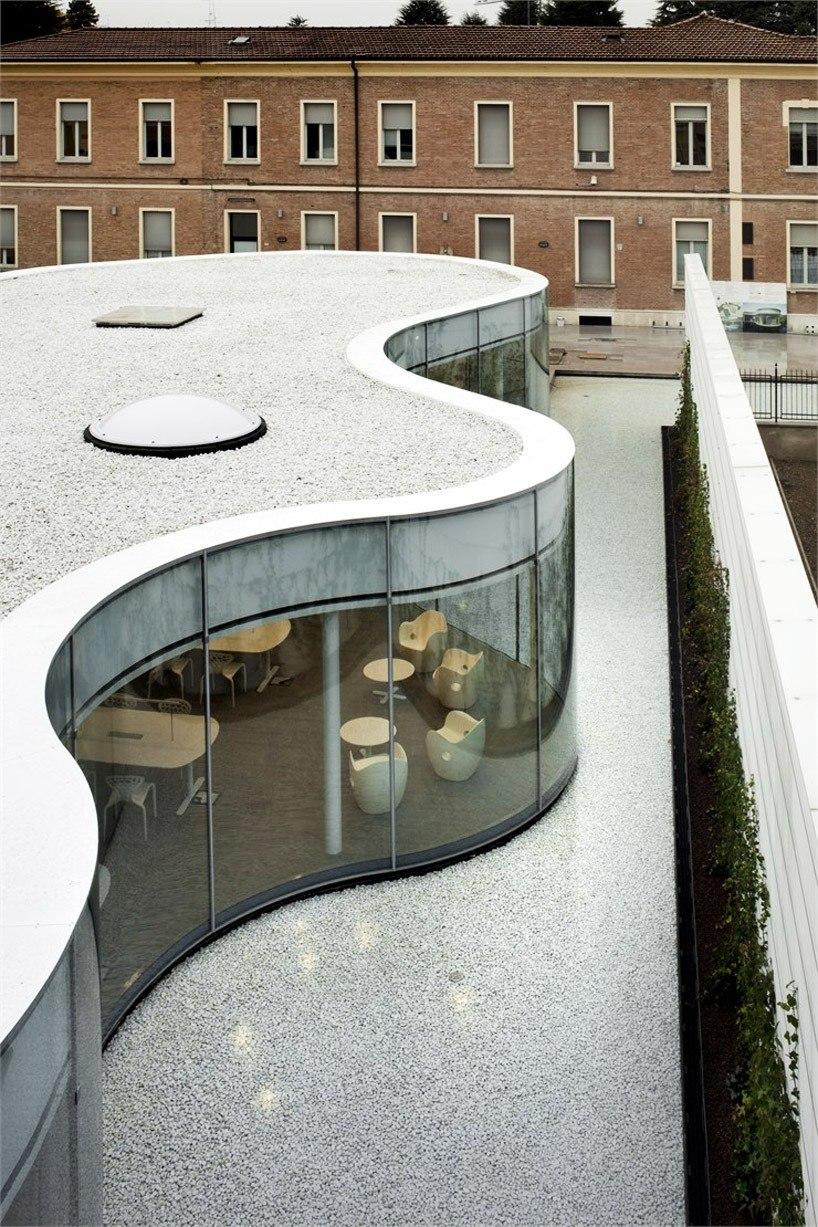 The bright interior of the MABIC Library, with white tables, delicate chairs, and a green courtyard