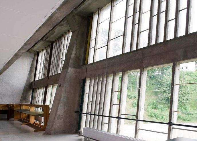 The interior of the Maison de la Culture in Firminy with an inclined glazed wall and concrete supports