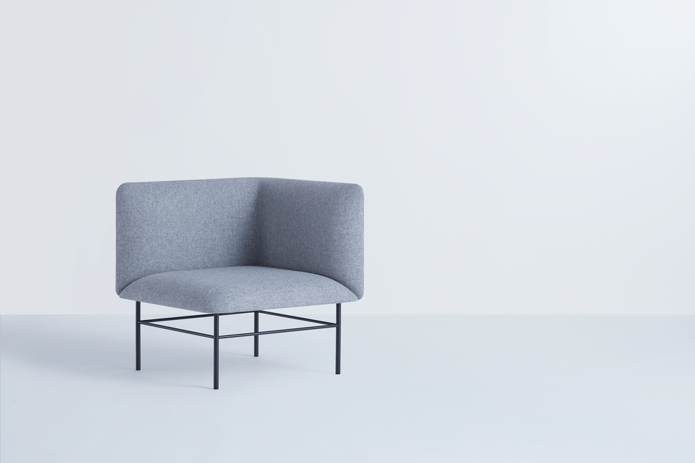 Grey upholstered armchair with an angular back on a black metal base
