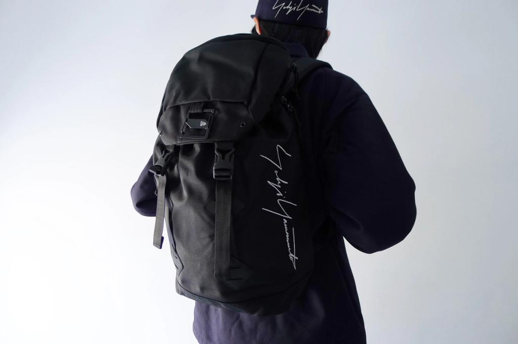 A black New Era backpack with Yohji Yamamoto's signature on the back of a person