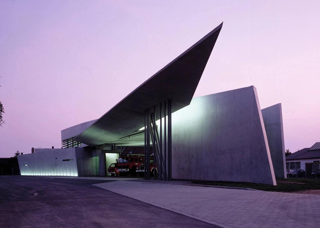 The Vitra fire station at dusk, a red fire engine visible beneath the canopy