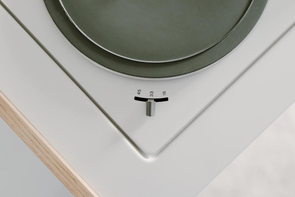 The green turntable platter and the 45, 33, 16 speed selector on the white cabinet