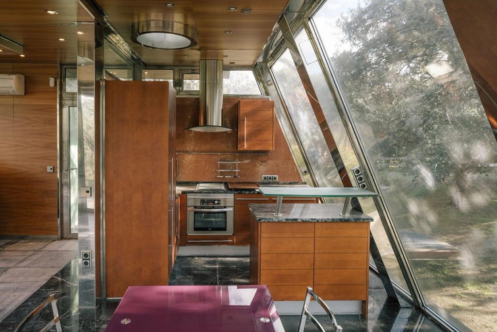 The kitchen of the house, with angled glass walls and a view into the forest
