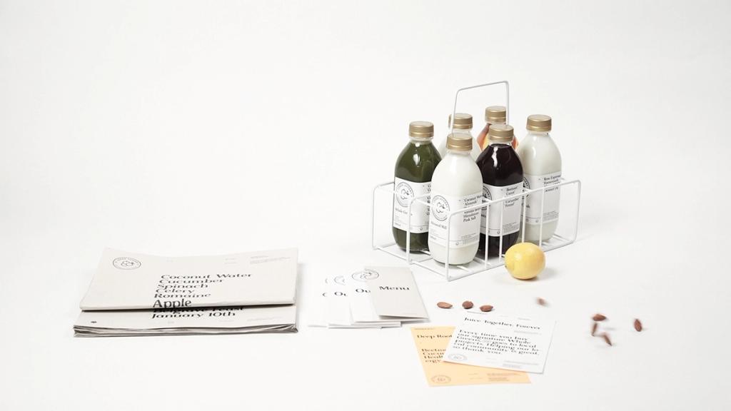 Бутылки соков Leeds Juicery в переноске и печатные материалы на белом фоне
