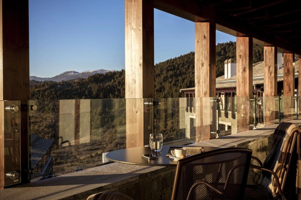 Balcony with wooden posts and a small table, looking out over the forested mountains of Greece