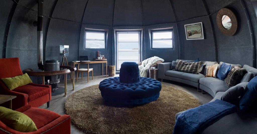 Interior of a domed living room with a blue sofa, a red armchair and a stove