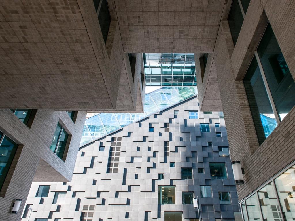 A view from below of the narrow passage between buildings in the Barcode district, featuring a grey-and-white patterned facade