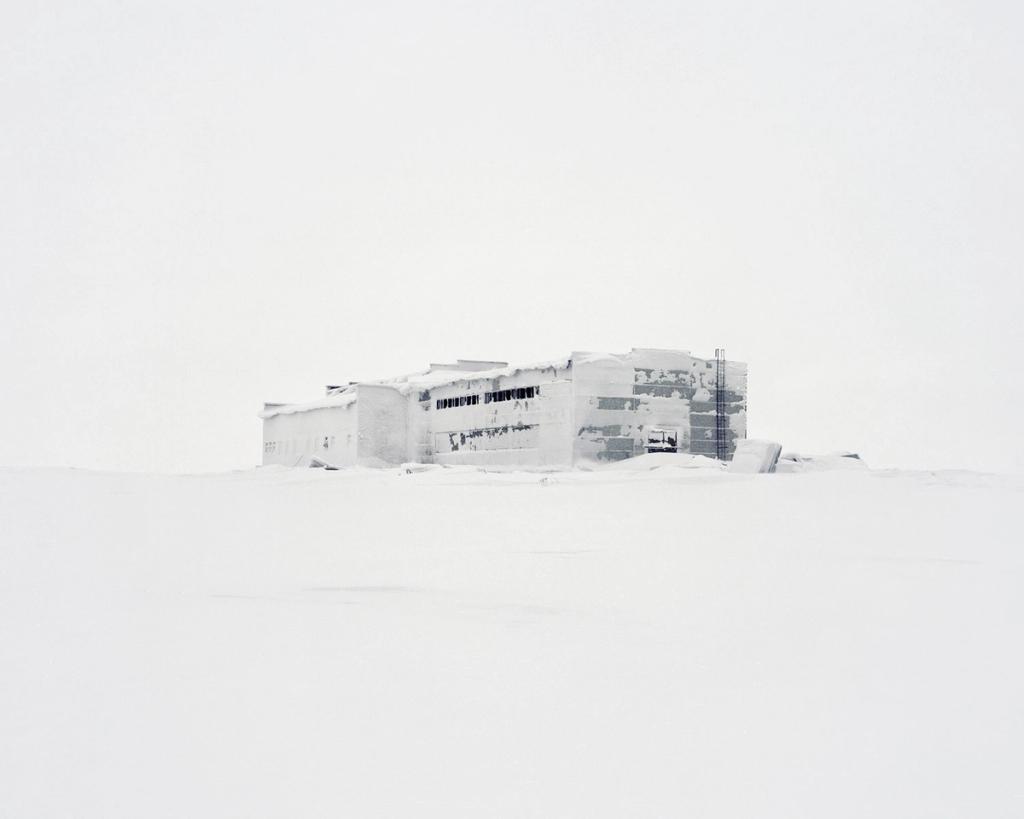 An abandoned industrial building with broken windows, blanketed by a thick layer of snow