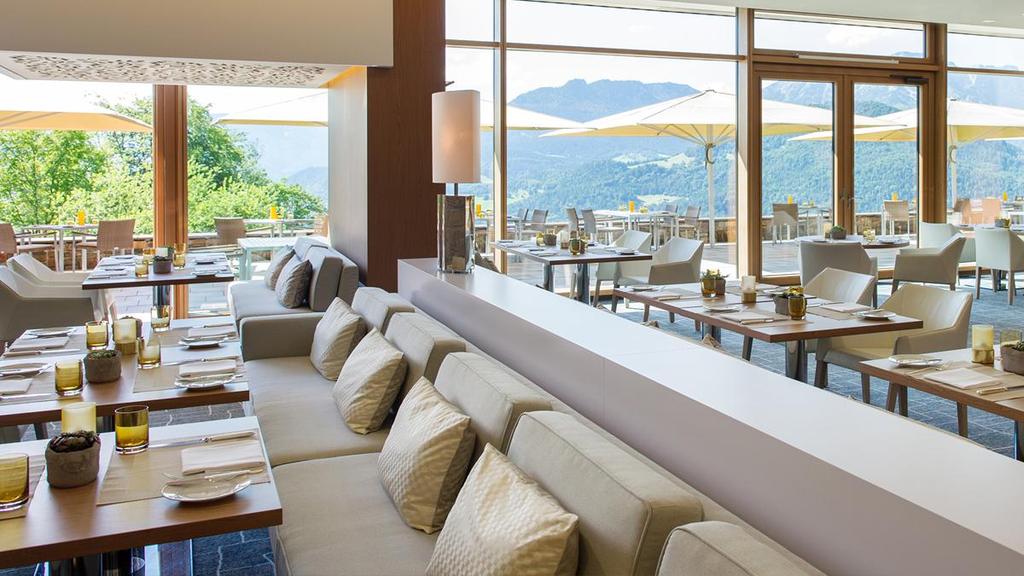 The hotel restaurant with panoramic windows and a terrace set against the Bavarian Alps