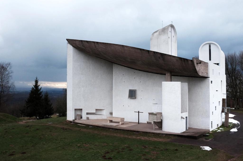 The Chapel of Ronchamp, a white volume with a canopy over the outdoor altar