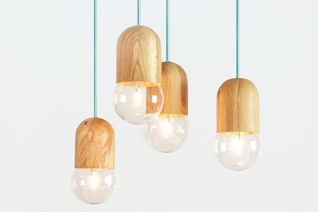 A cluster of pendant lights with wooden shades and glass spheres on turquoise cords