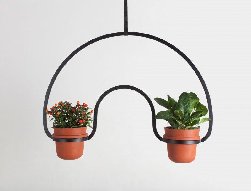 A hanging planter by Katerina Kopytina, made from bent black metal and holding two terracotta pots