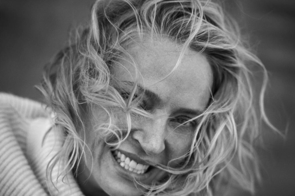 Black-and-white portrait of a smiling fair-haired woman with tousled hair