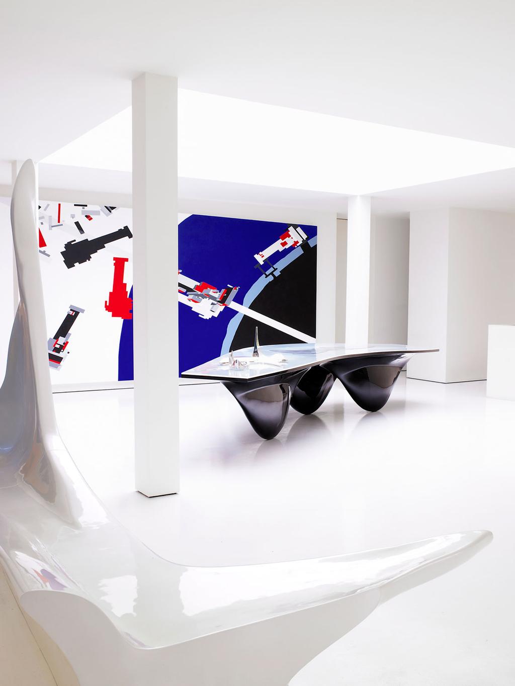White gallery interior with a black wave-form table and a Suprematist painting by Malevich