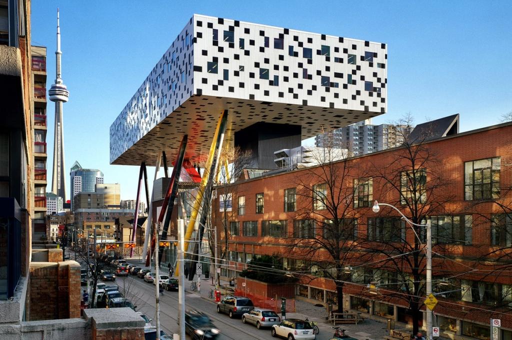Чёрно-белый корпус OCAD на цветных опорах-ногах на фоне башни Си-Эн в Торонто