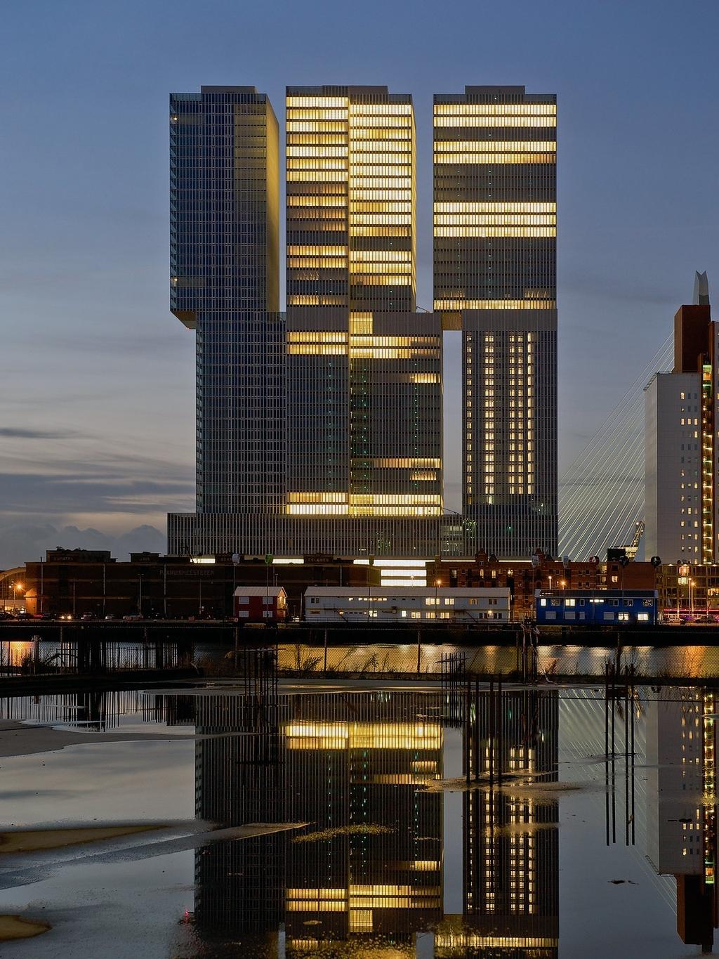 Подсвеченные вечером башни комплекса De Rotterdam, отражённые в воде