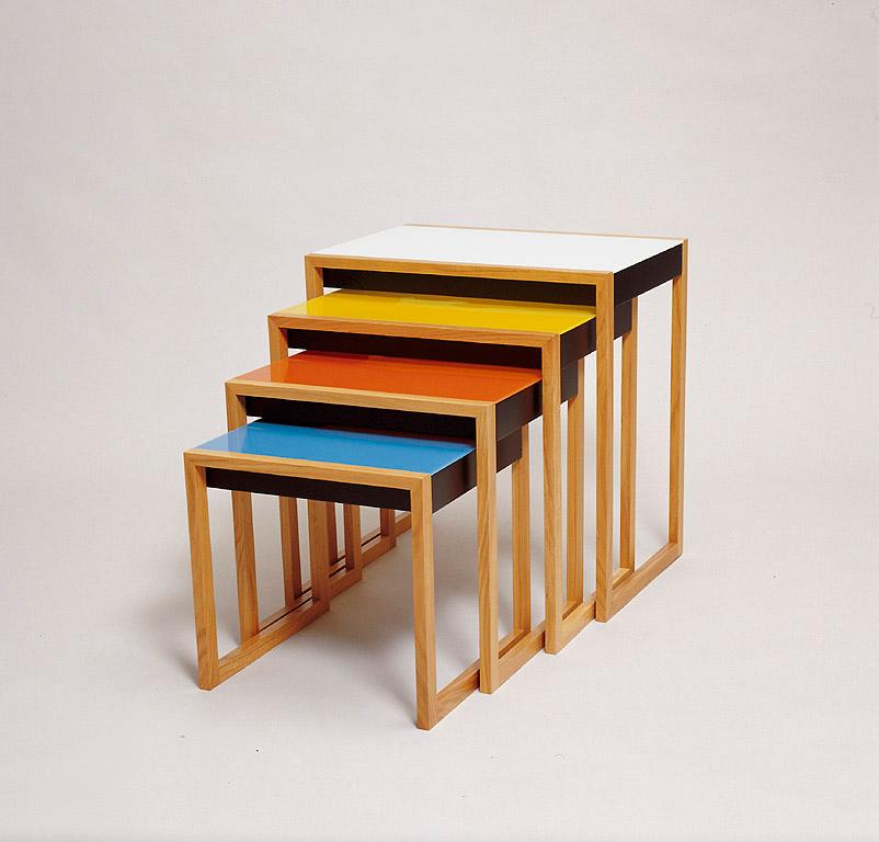 A set of four nesting tables by Josef Albers with white, yellow, orange and blue tops