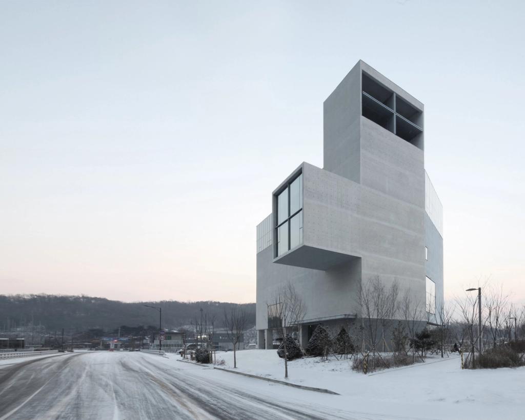 Бетонная церковь RW Concrete Church из сдвинутых блоков зимой у заснеженной дороги