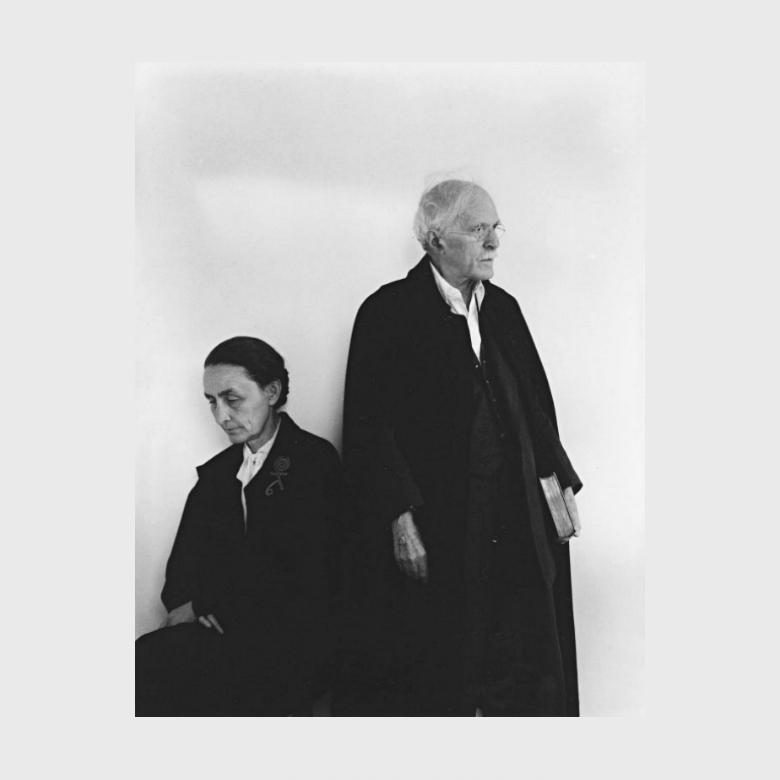 A black-and-white photograph of an elderly O'Keeffe and Alfred Stieglitz in dark clothing