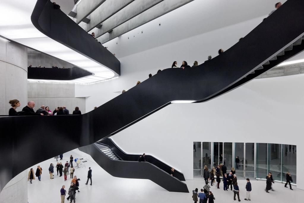 A black curving staircase and parapets within the white atrium of the MAXXI museum in Rome