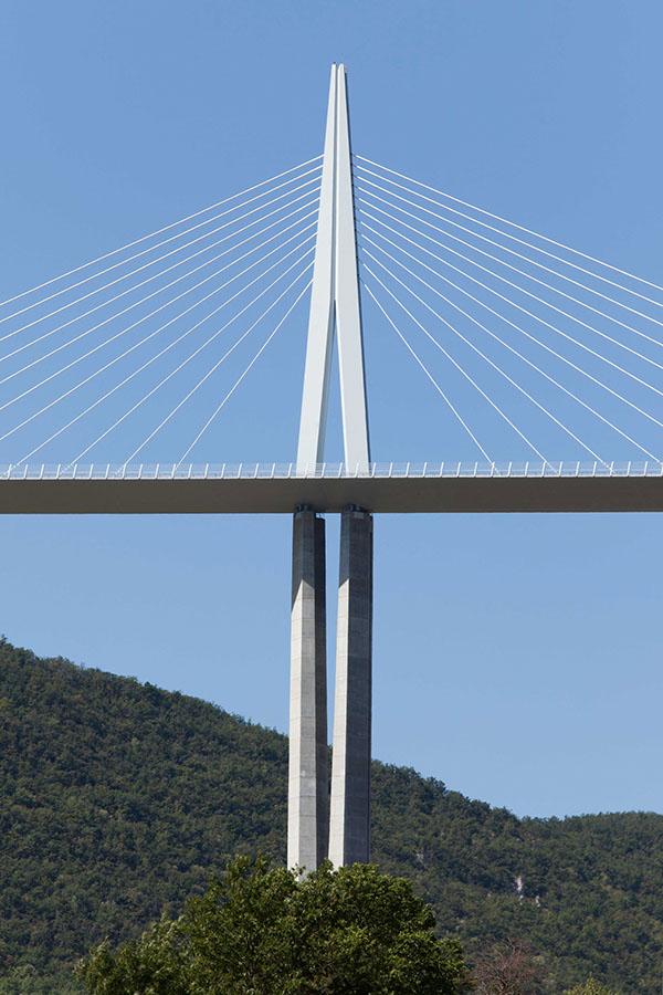 The long, curving deck of the Millau Viaduct on concrete piers above a rolling valley