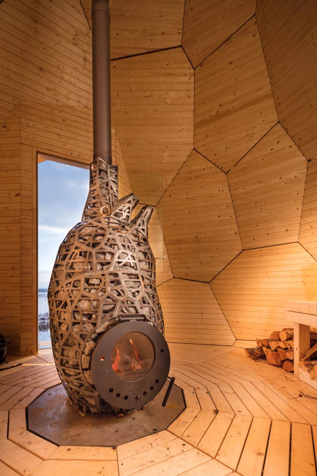 The wooden interior of the sauna, featuring an ornate stone stove in the shape of a heart with a burning fire