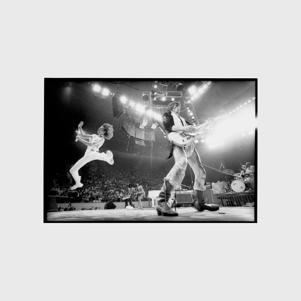 A black-and-white concert photograph of The Rolling Stones on a brightly lit stage