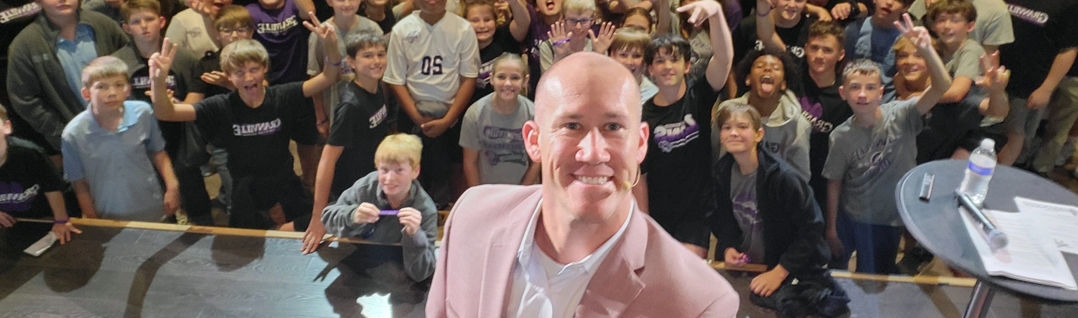 Taylor Candella taking an on-stage selfie with his audience of students.