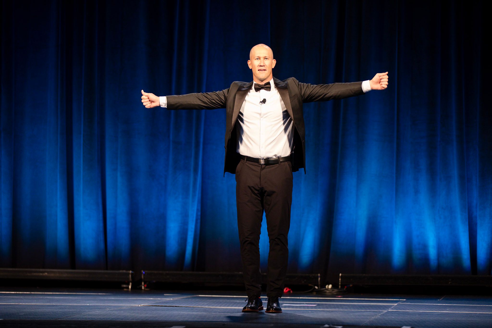 Taylor Candella delivering a keynote speech on stage, gesturing passionately to an audience.