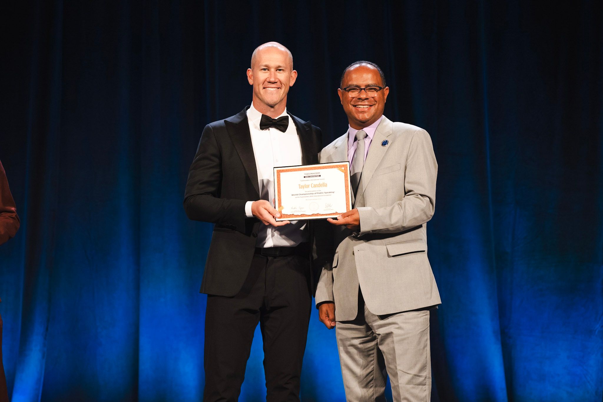 Taylor Candella on stage at the 2025 Toastmasters World Championship, accepting his award for placing in the Top 28 out of 30,000 global contestants.