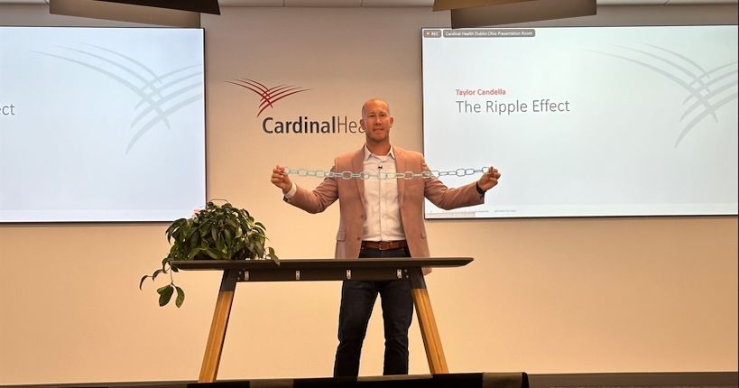 Taylor Candella delivering a keynote speech at Cardinal Health, using a chain link prop to demonstrate the 'Ripple Effect'.