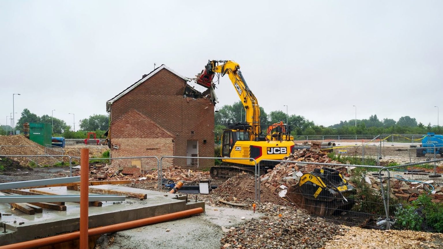 Tracked excavator pulling down the roof of a brick house during a complete house demolition in Hampshire.