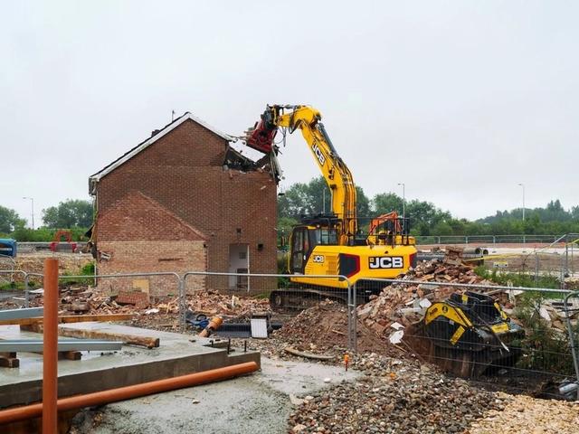 Tracked excavator pulling down the roof of a brick house during a complete house demolition in Hampshire.