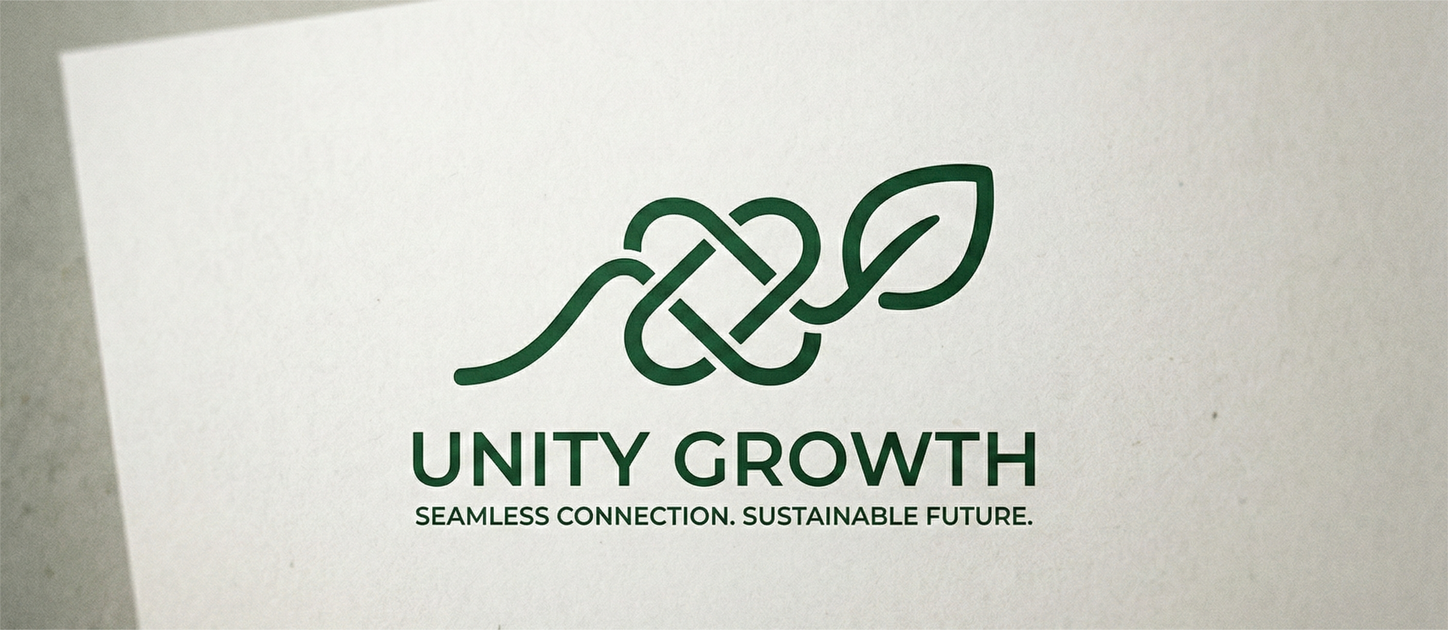 A detailed close-up photograph of a deep forest-green logo printed centrally on light-colored textured paper. Above the text is a continuous line-art symbol that features an intertwined knot pattern transitioning into a stylized leaf at the end. Below this icon, in all-caps text, is the company name "UNITY GROWTH". Directly underneath the main text, in smaller caps, is the tagline: "SEAMLESS CONNECTION. SUSTAINABLE FUTURE." The logo is shot from an elevated perspective.
