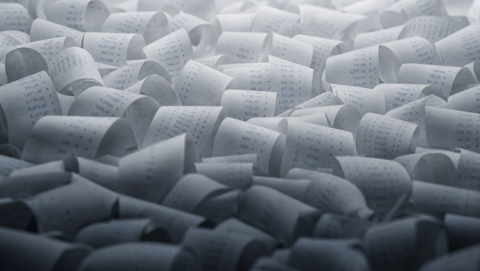 Coiled receipt-style paper strips with numeric rows, symbolizing health insurance (PKV) costs in Germany."