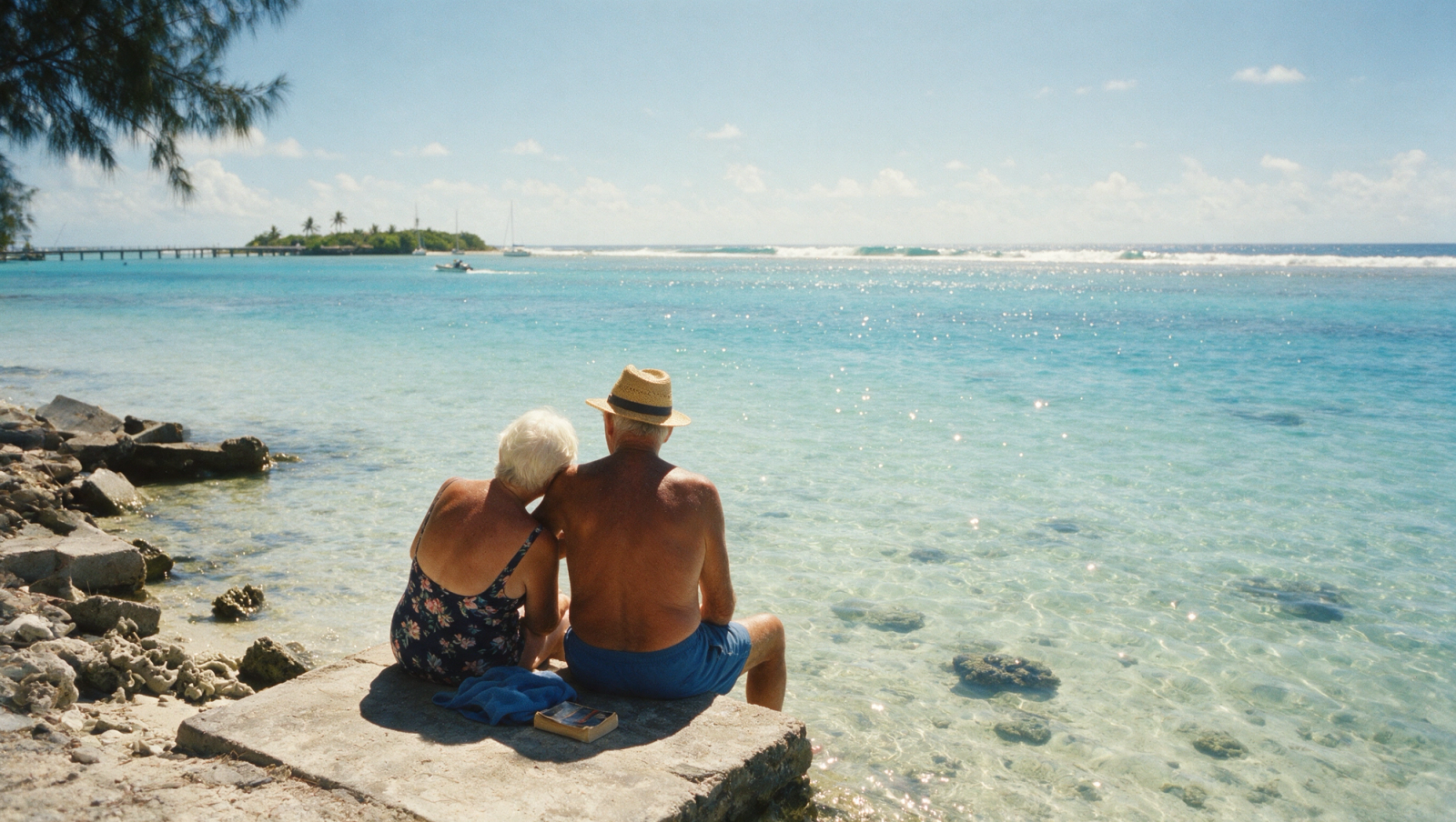A retired couple sitting on a beach, looking out at the sea