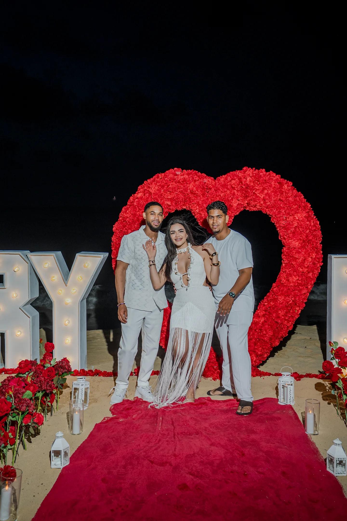 Couple et coordinatrice près du décor de demande en forme de cœur sur la plage